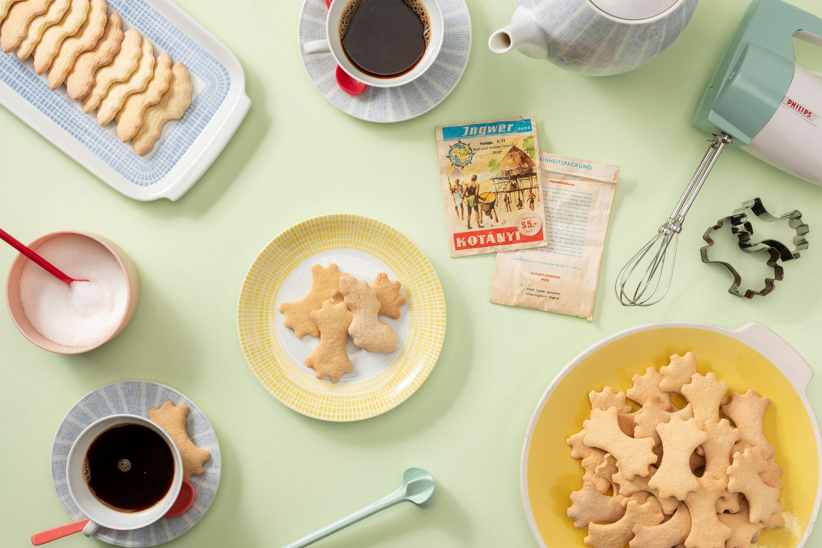 Ciasteczka imbirowe na talerzyku i zestaw do kawy w pastelowych kolorach.