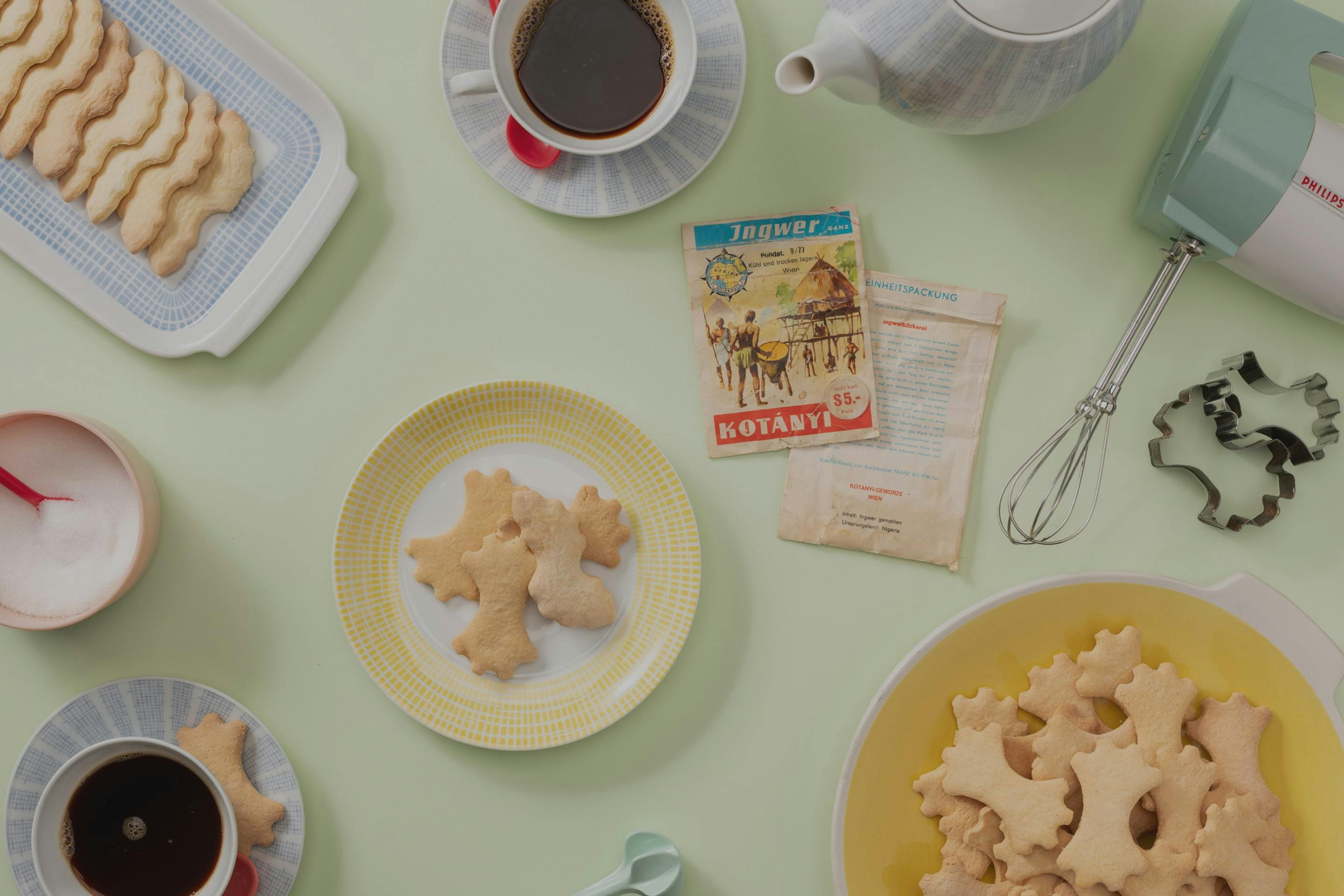 Ciasteczka imbirowe na talerzyku i zestaw do kawy w pastelowych kolorach.